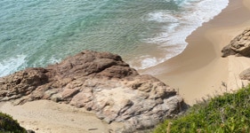 une plage au sable rosé et à la mer turquoise en Corse